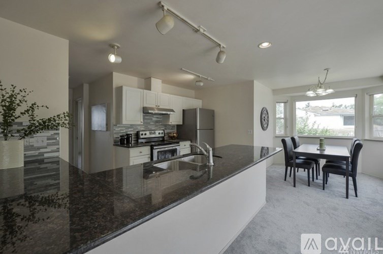 A modern kitchen with granite countertops and a dining area with a table and chairs.