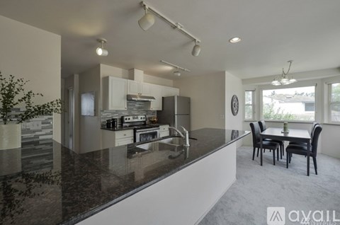 A modern kitchen with granite countertops and a dining area with a table and chairs.