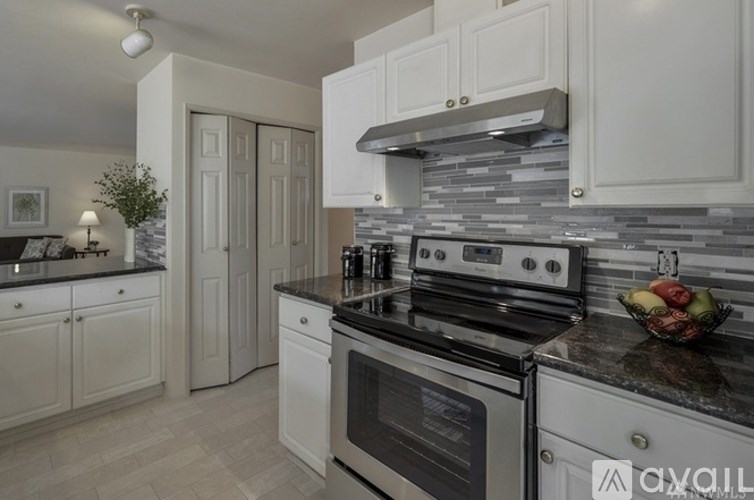 A modern kitchen with white cabinets and a black countertop.
