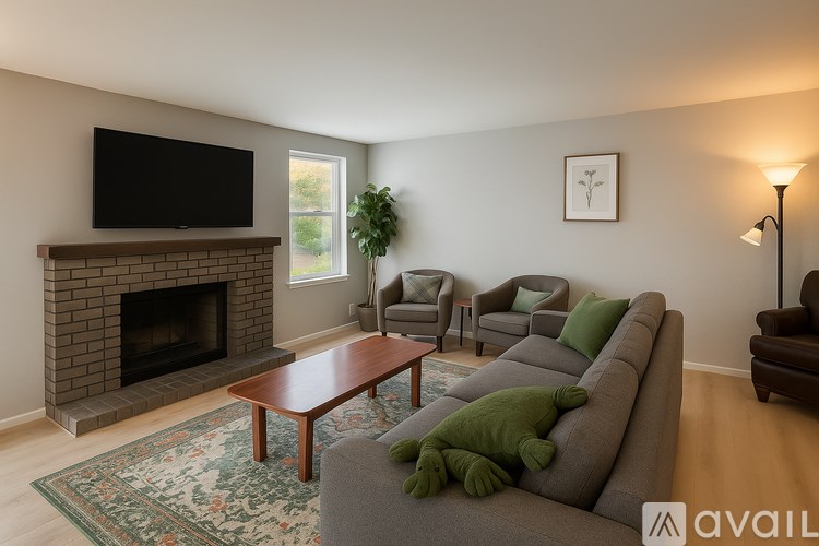 A living room with a grey couch, a coffee table, a fireplace, and a flat screen TV mounted above it.