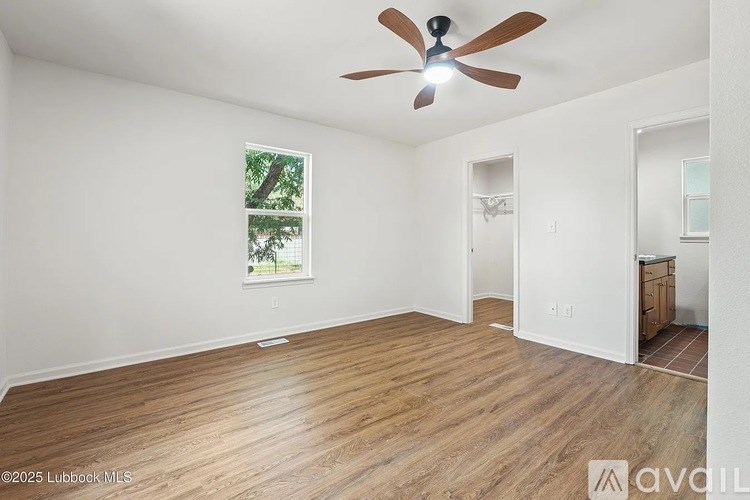A room with a ceiling fan and wooden flooring.