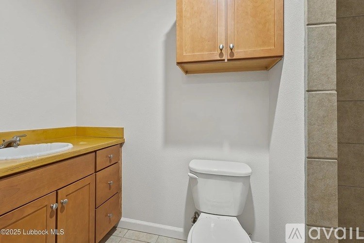A white toilet is in a bathroom with wooden cabinets.