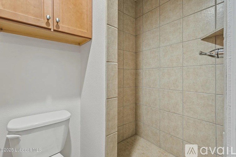 A bathroom with a toilet and a tiled shower area.