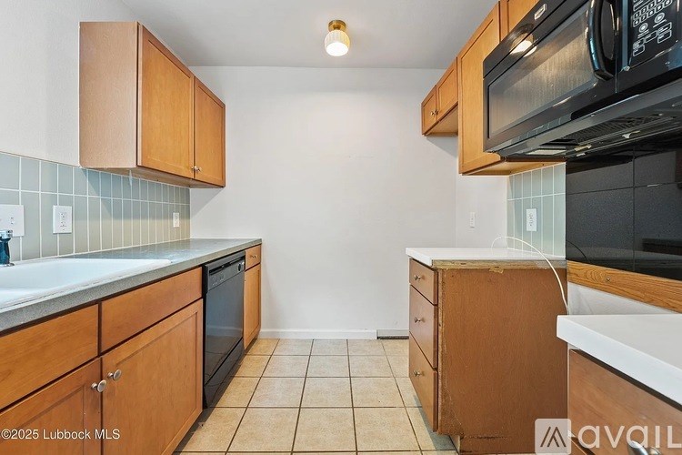 A kitchen with wooden cabinets and a black microwave above the counter.