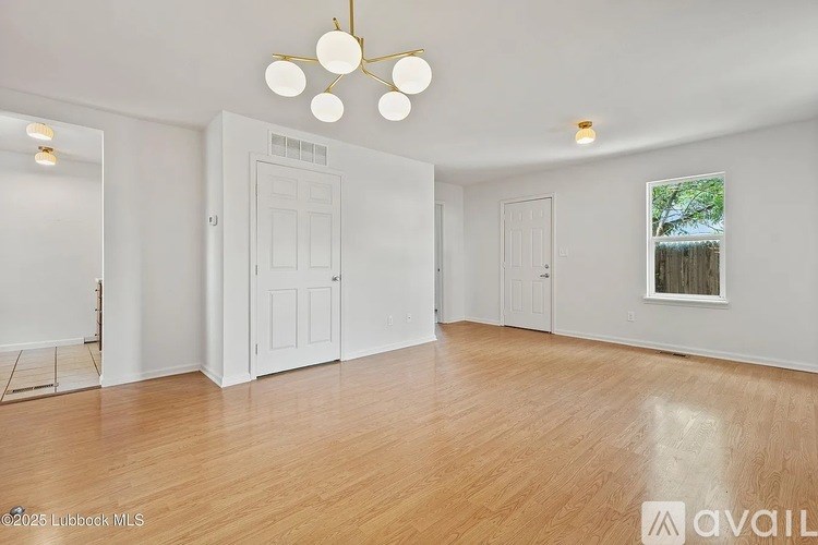 A spacious room with wooden flooring and white walls.