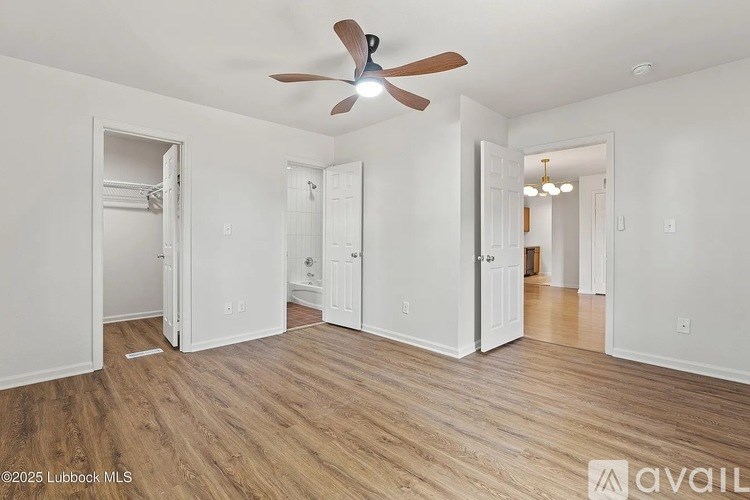 A room with a ceiling fan and wooden flooring.