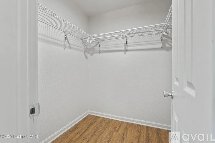 A white closet with a wooden floor and a white door.