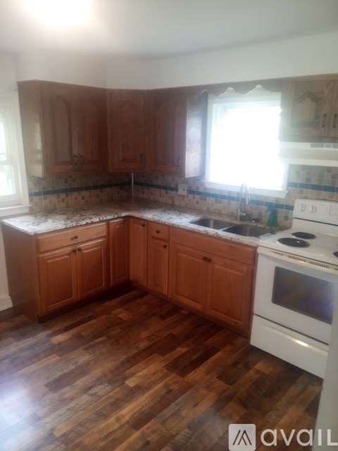 A kitchen with wooden cabinets and a white stove top oven.