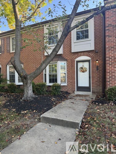 A red brick house with a white door and a tree in front.