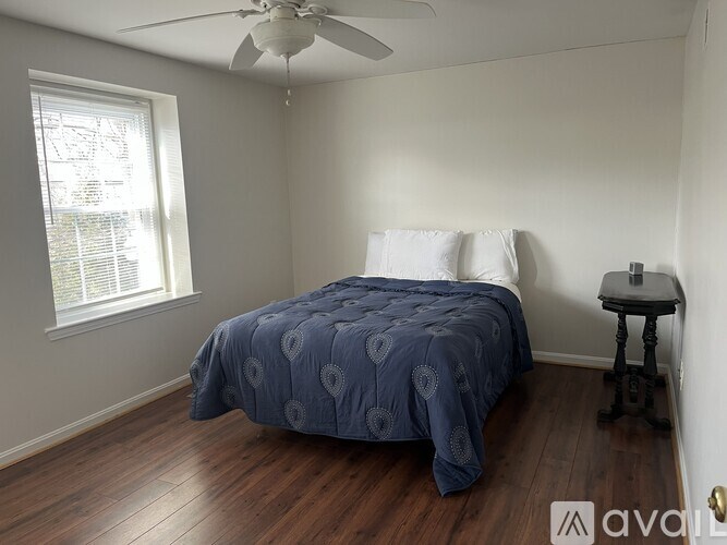 A bedroom with a bed, a fan, and a window.