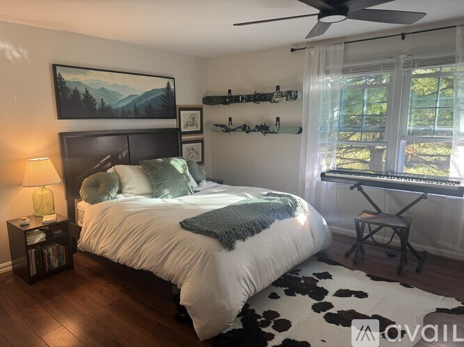 A bedroom with a large bed, a ceiling fan, and a painting on the wall.
