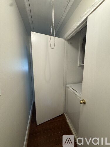 A white door with a gold handle is in a narrow hallway.