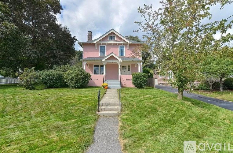 A pink house with a white fence and a gravel path leading to the front door.
