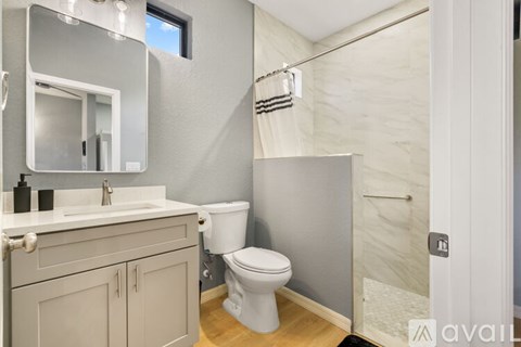 A bathroom with a toilet, sink, and a mirror.