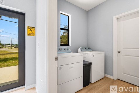 A laundry room with a washer and dryer and a caution sign on the door.
