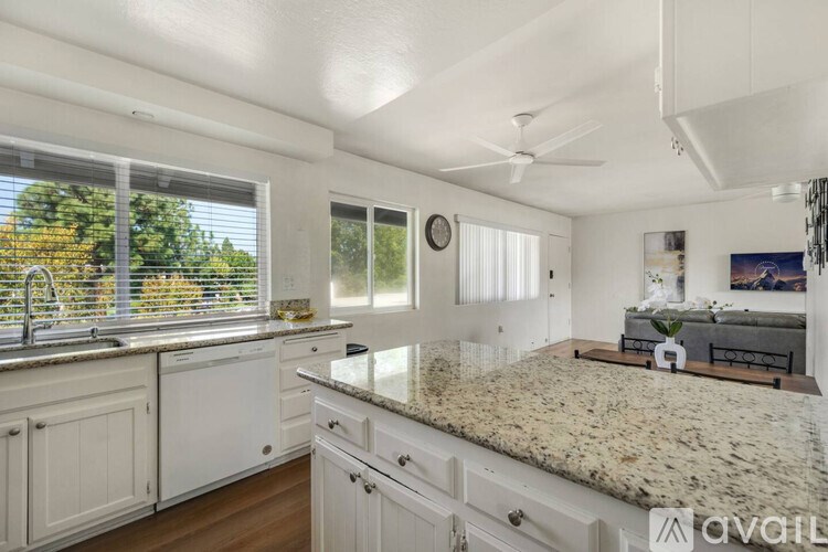 A kitchen with white cabinets and a granite countertop.