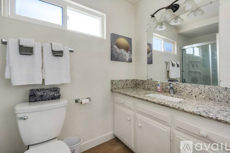 A bathroom with a toilet, sink, and mirror.