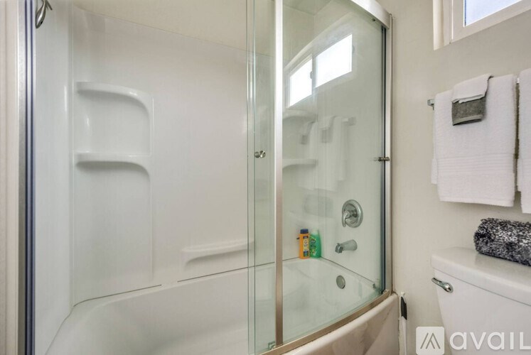 A bathroom with a glass shower door and a white towel hanging on the wall.