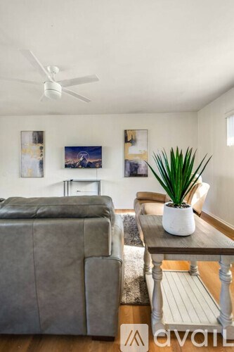 A living room with a grey couch, a coffee table, and a plant.