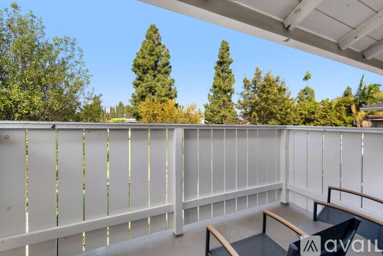 A balcony with a table and chairs overlooking trees.