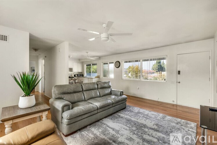 A living room with a grey sofa and a ceiling fan.