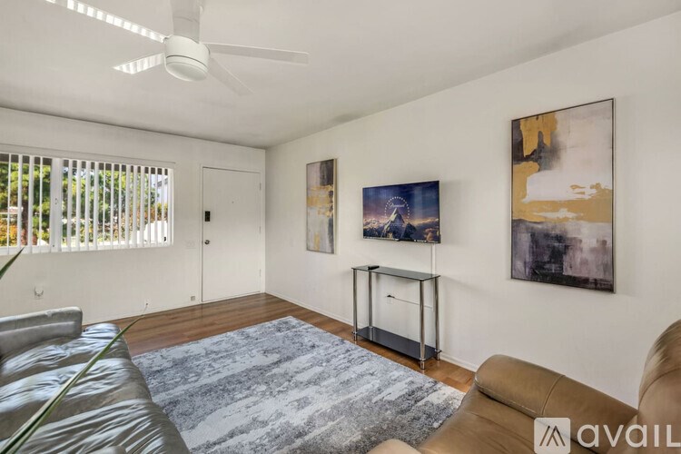 A living room with a brown couch, a blue rug, and two paintings on the wall.