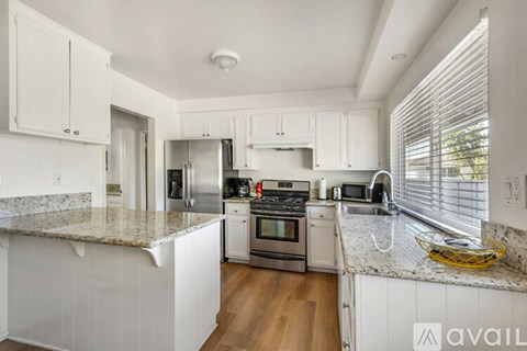 A kitchen with white cabinets and granite countertops.