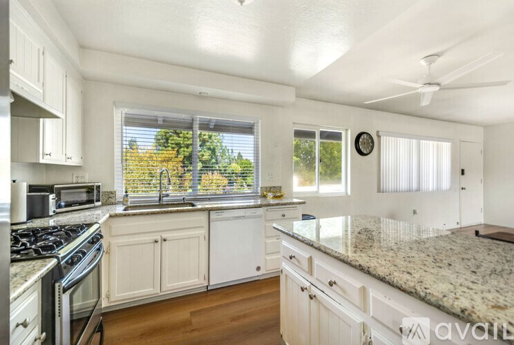A kitchen with white cabinets and granite countertops.