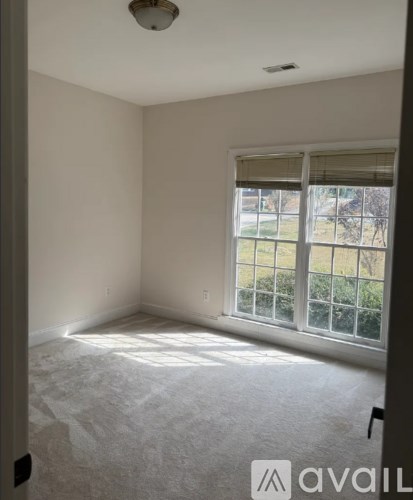 A room with a window and a carpeted floor.