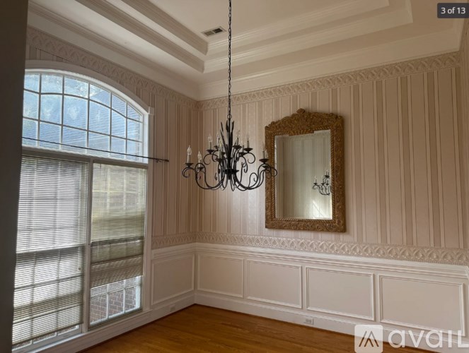 A room with a chandelier, mirror, and wooden floors.