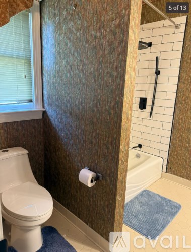 A bathroom with a toilet, a window, and a shower.