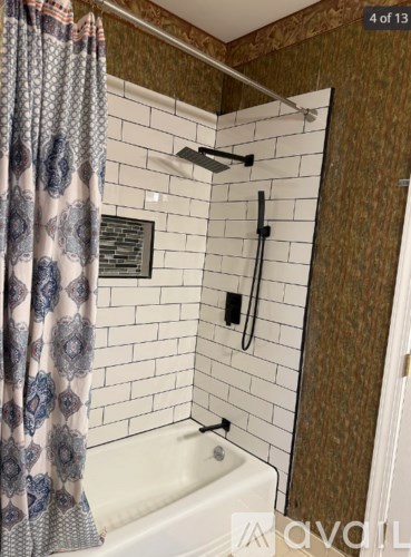 A shower area with a white tub and a shower head.