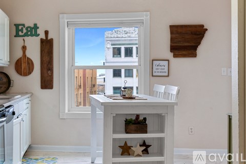 A kitchen with a white table and chairs and a window with a view of a building outside.