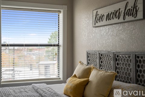 A bedroom with a bed, pillows, and a sign that says "love never fails".