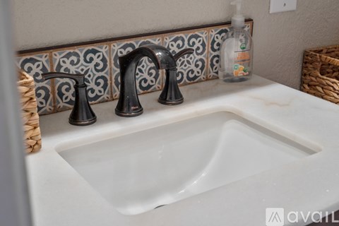 A white sink with a black faucet and a soap dispenser on a counter.