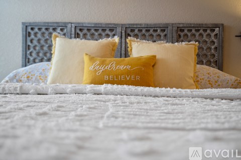 A bed with two pillows that say "daydream believer" on them.