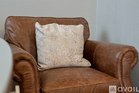 A brown leather chair with a pillow on it.