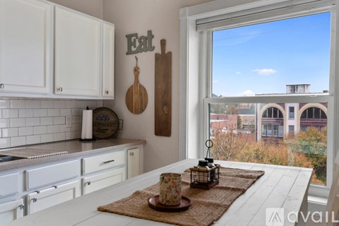 A kitchen with white cabinets and a window overlooking a cityscape.