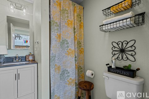 A bathroom with a white toilet and a floral shower curtain.