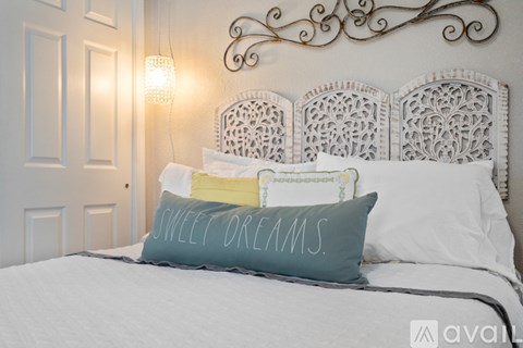 A bed with a white headboard and a pillow that says "Sweet Dreams".