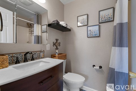 A bathroom with a white sink, toilet, and a mirror.