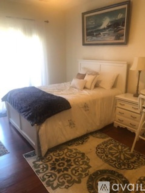 A bedroom with a large bed and a painting on the wall.