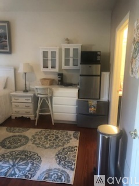 A kitchen with a fridge, a stove, and a table with a lamp.