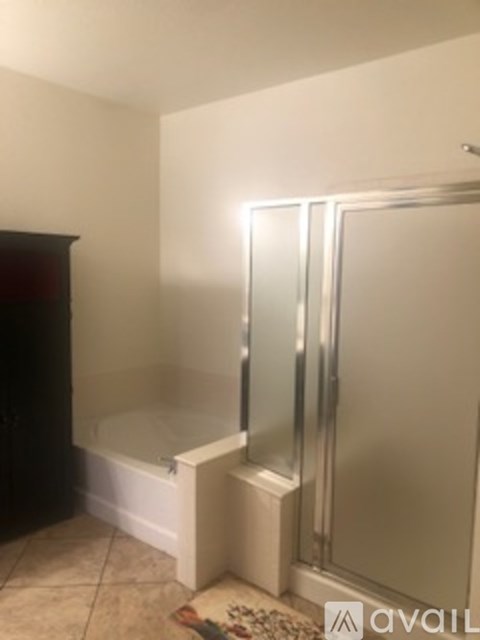 A bathroom with a glass shower door and a rug on the floor.