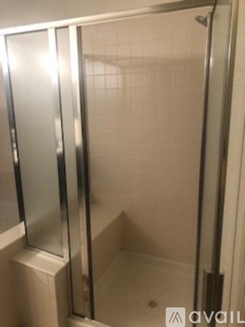 A shower stall with a glass door and a white tiled wall.