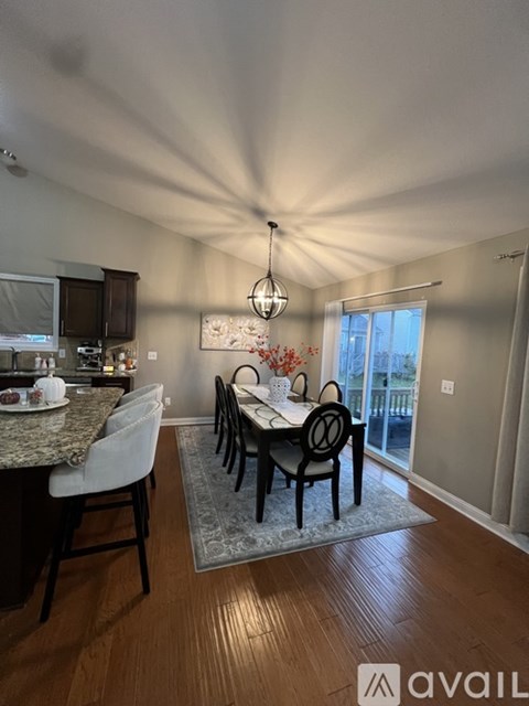 A dining room with a table set for four and a kitchen area in the background.
