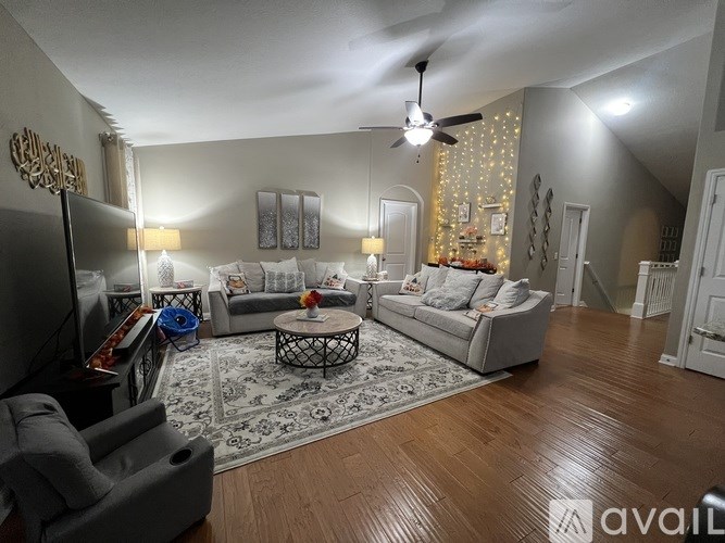 A living room with a grey couch, a coffee table, and a ceiling fan.