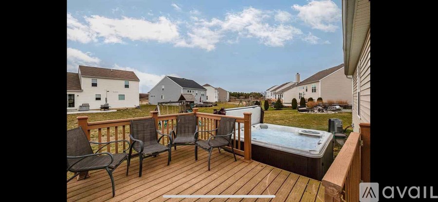 A hot tub is on a deck with chairs around it.