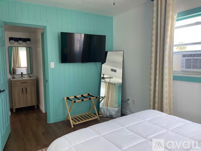 A bedroom with a bed, a TV, and a chair.