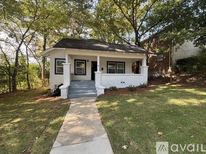A small white house with a black roof and a porch.